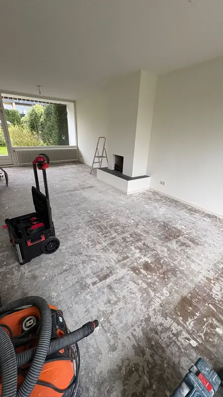 Woonkamer met de schouw nog volledig intact, vloer al gestript